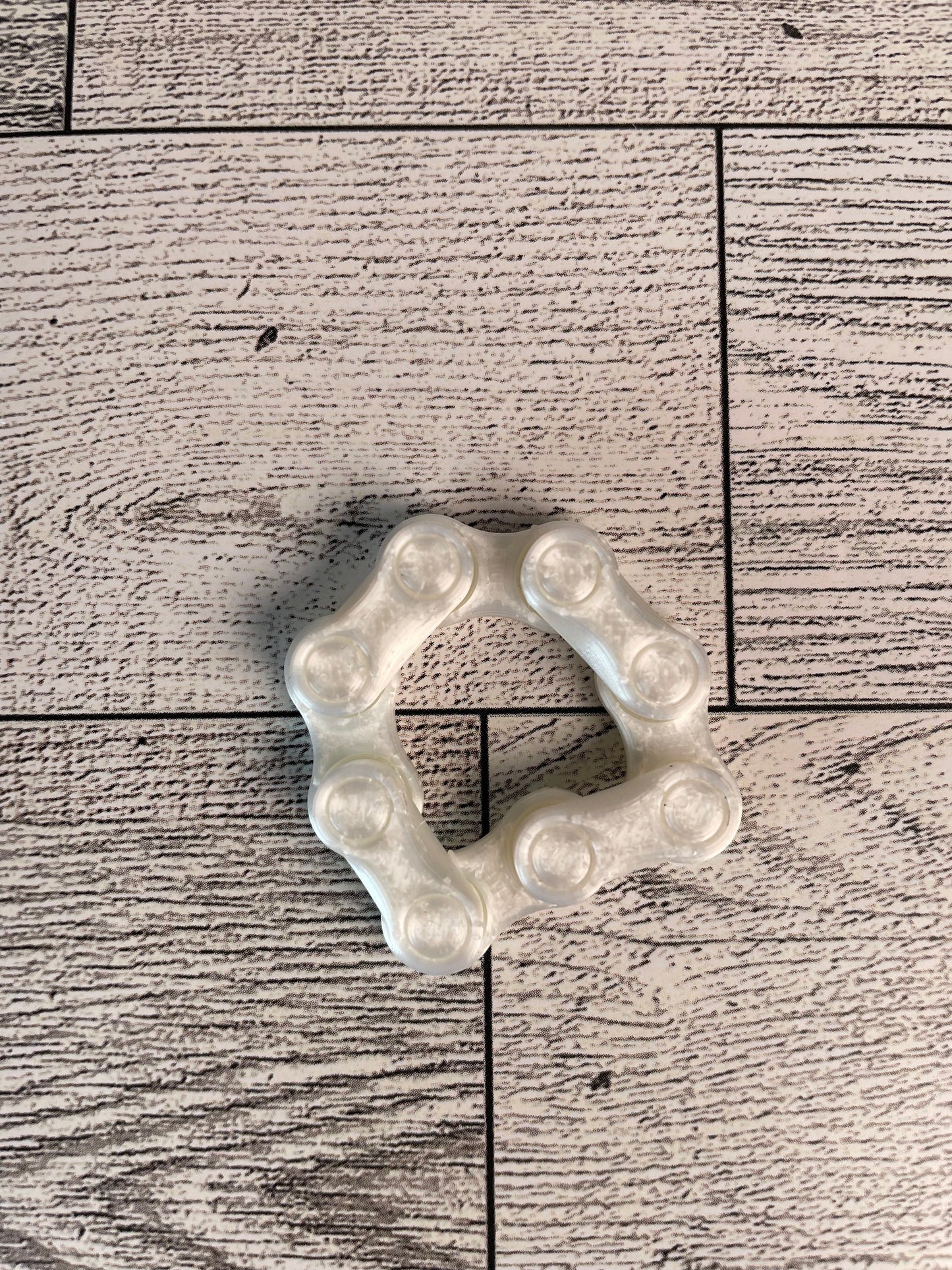 A shiny white chain link on a wood backdrop. The chain is arranged in a circle shape and there are four links