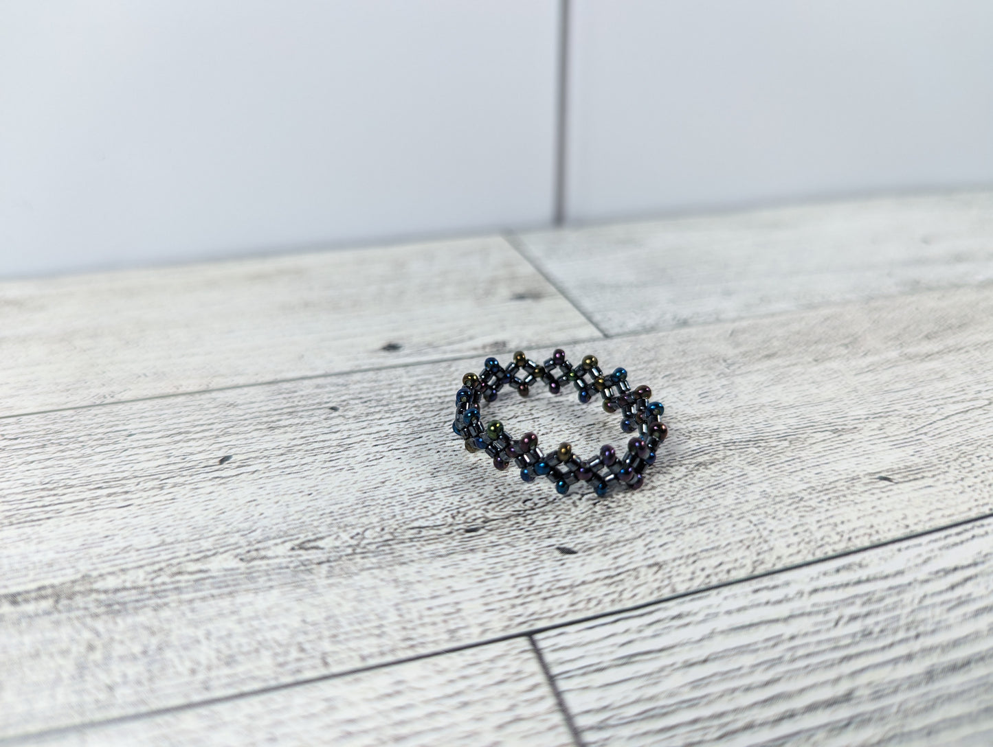A black ring placed on a wood grain surface with a tile backdrop.