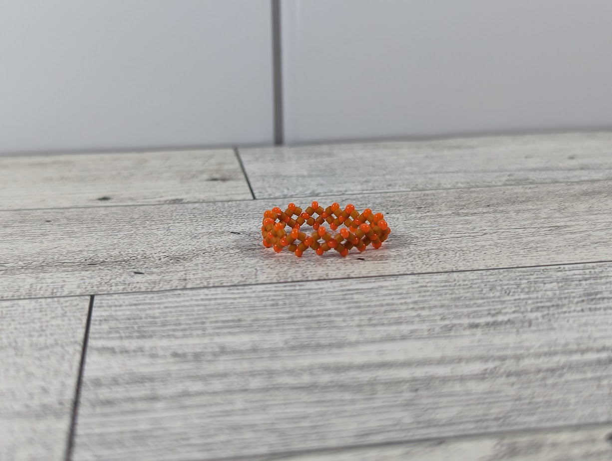 A orange ring with two shades placed on a wood grain surface with a tile backdrop.