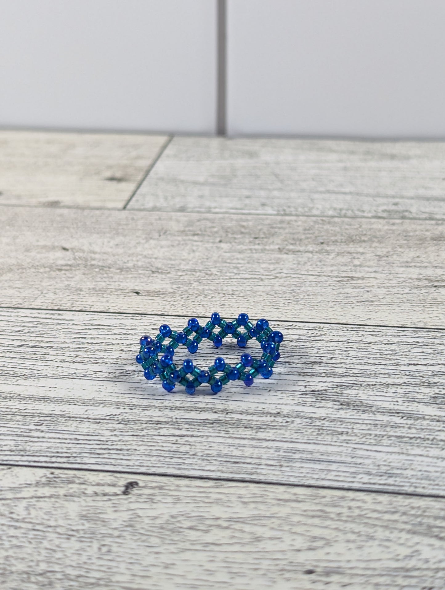 A blue ring placed on a wood grain surface with a tile backdrop.
