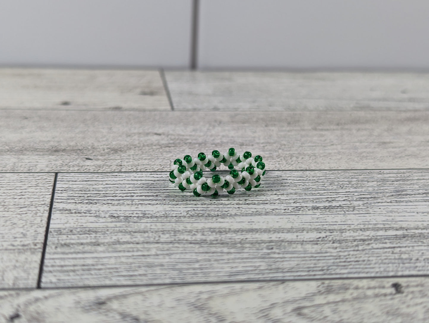 A green and white ring placed on a wood grain surface with a tile backdrop.