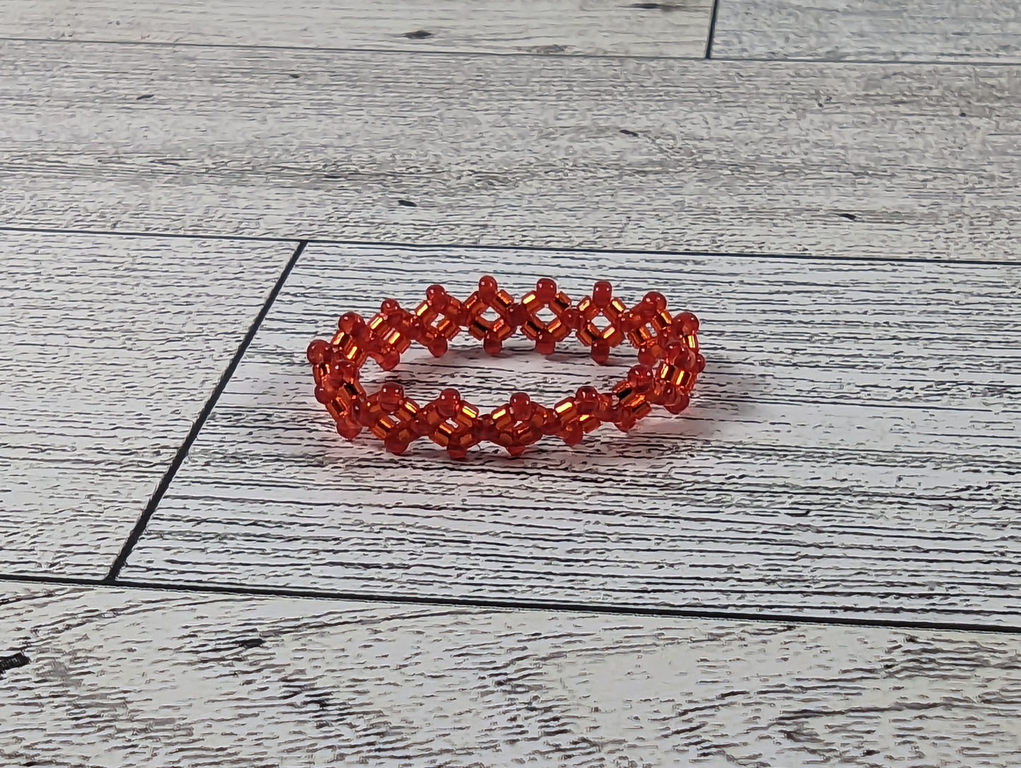 A red ring placed on a wood grain surface with a tile backdrop.