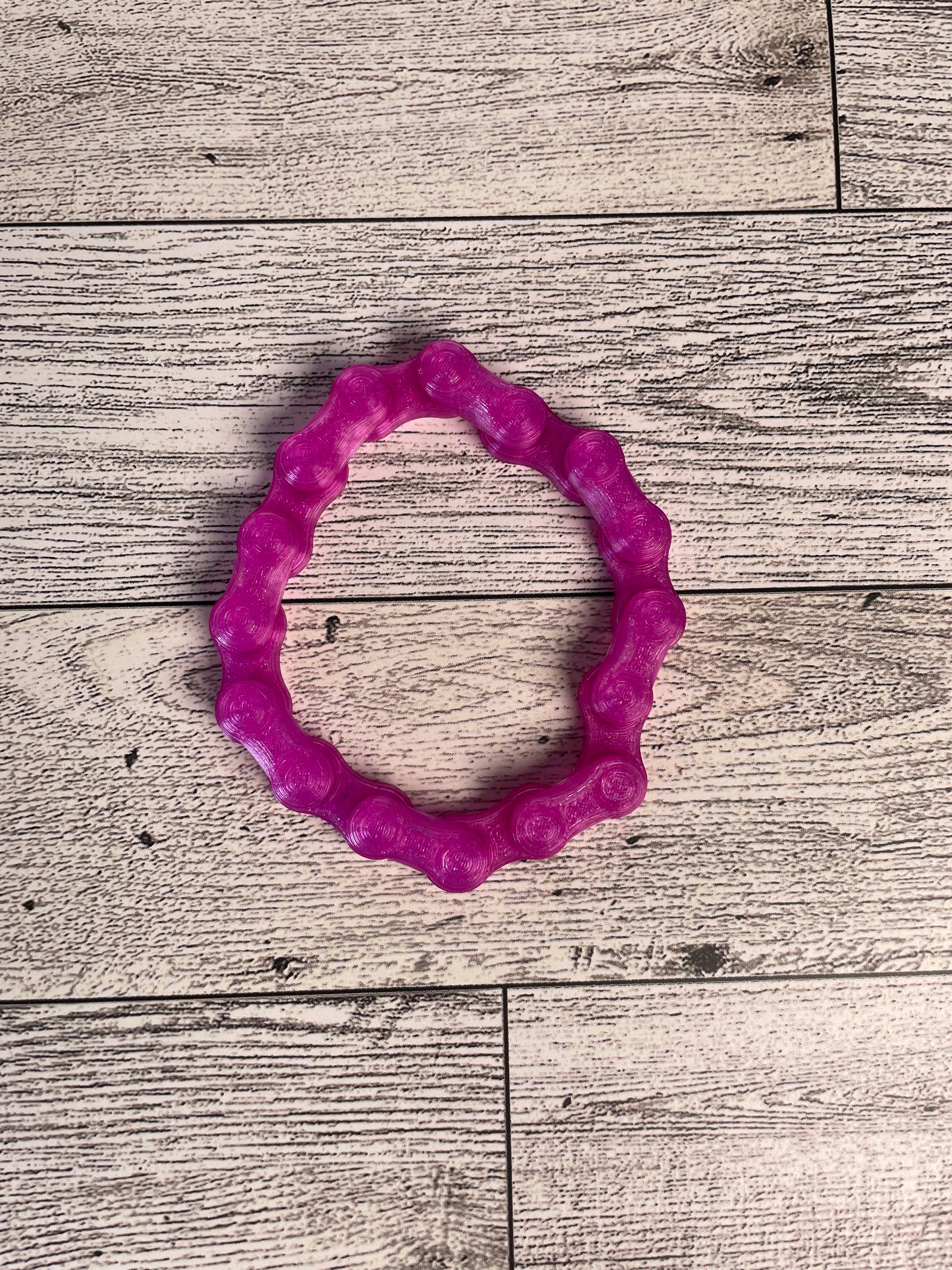 A translucent purple chain link on a wood backdrop. The chain is arranged in a circle shape and there are eight links.
