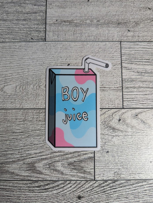 A juice box sticker with the words "BOY juice" on it. The colors are of the transmasculine flag. The backdrop is a light wood.